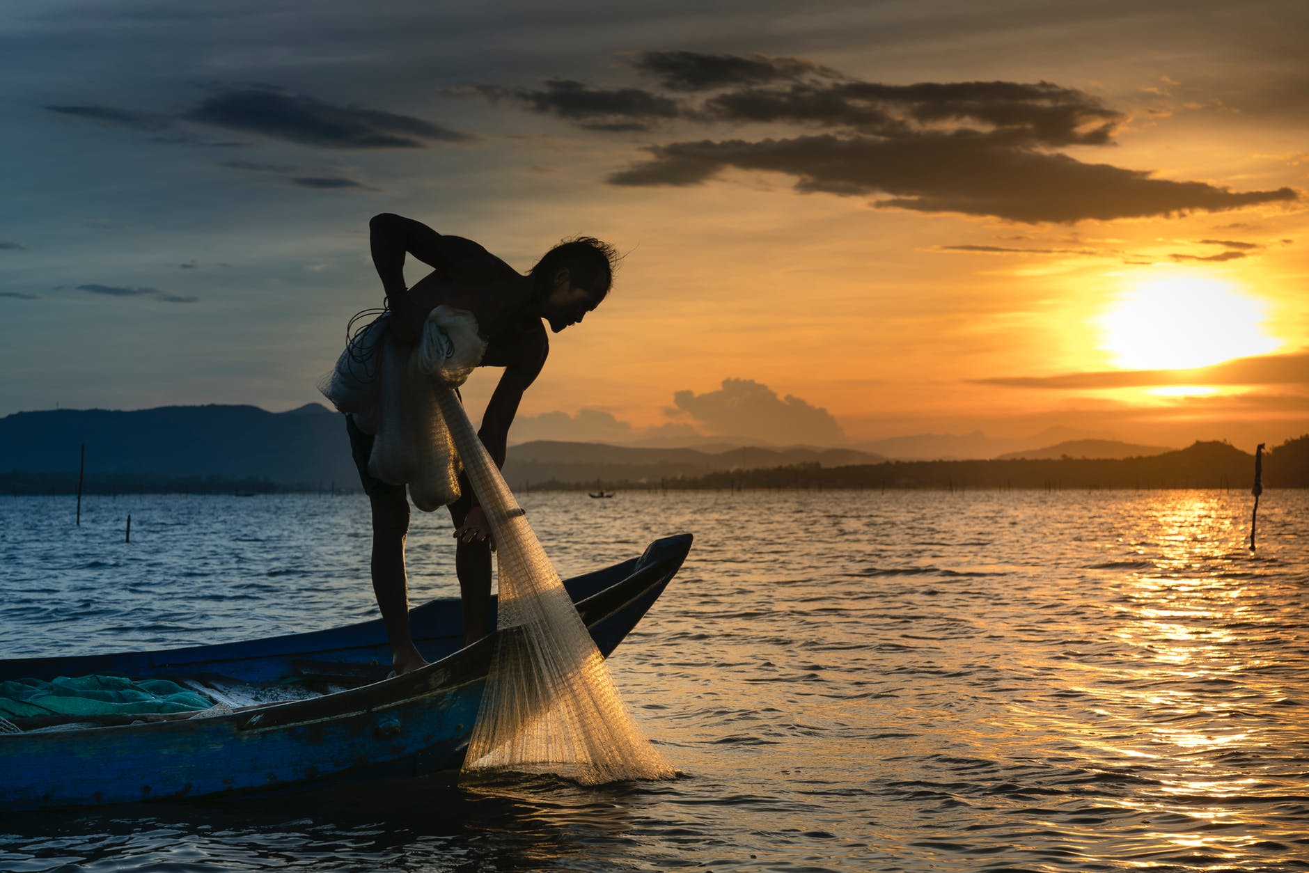 man on boat holding white mesh fishing net